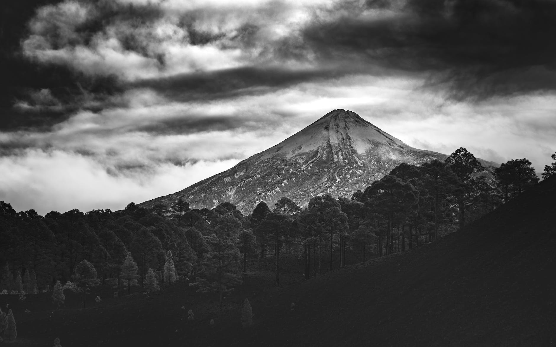 grayscale photo of mountain under cloudy sky