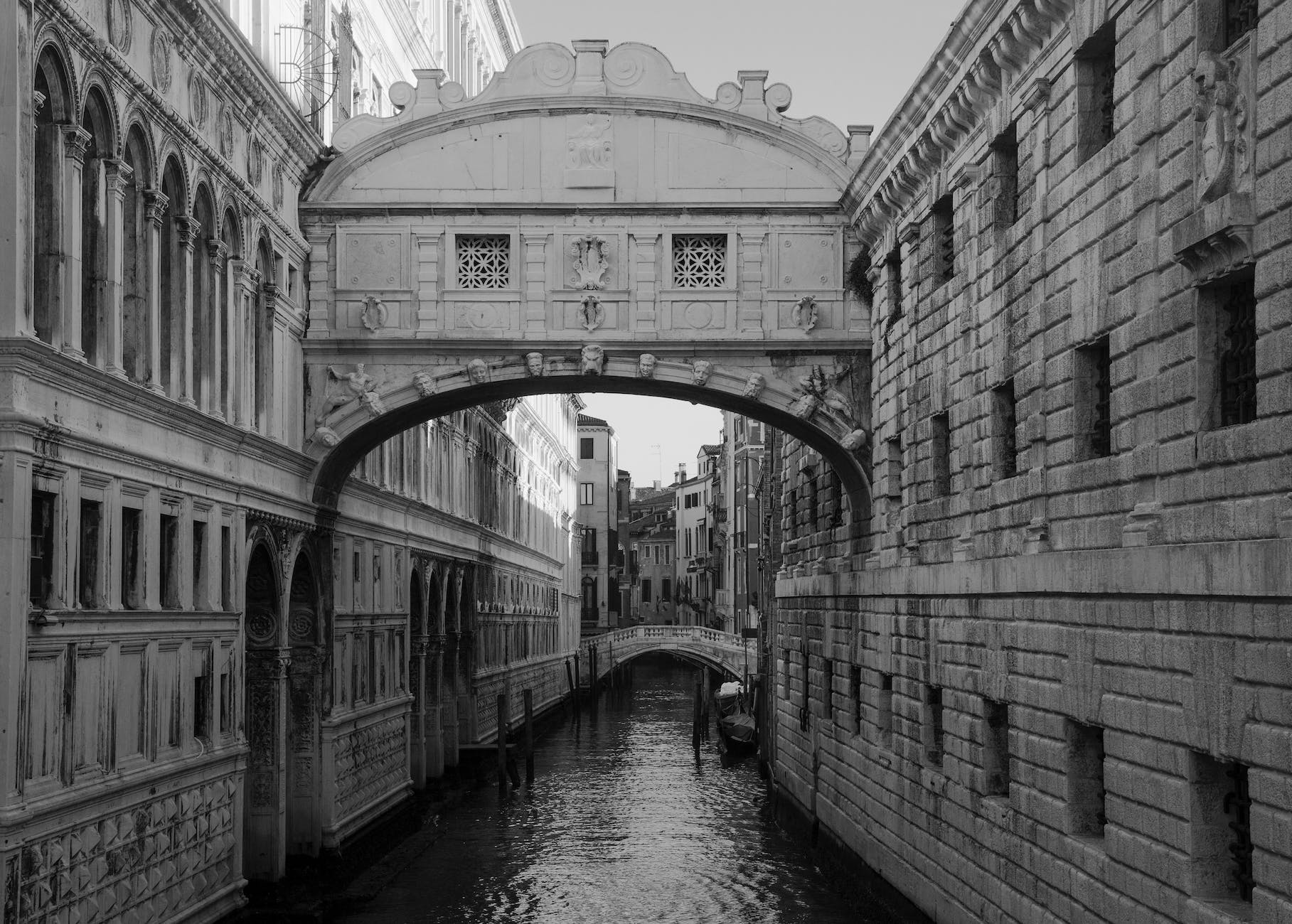 grayscale photo of an arch bridge over a canal