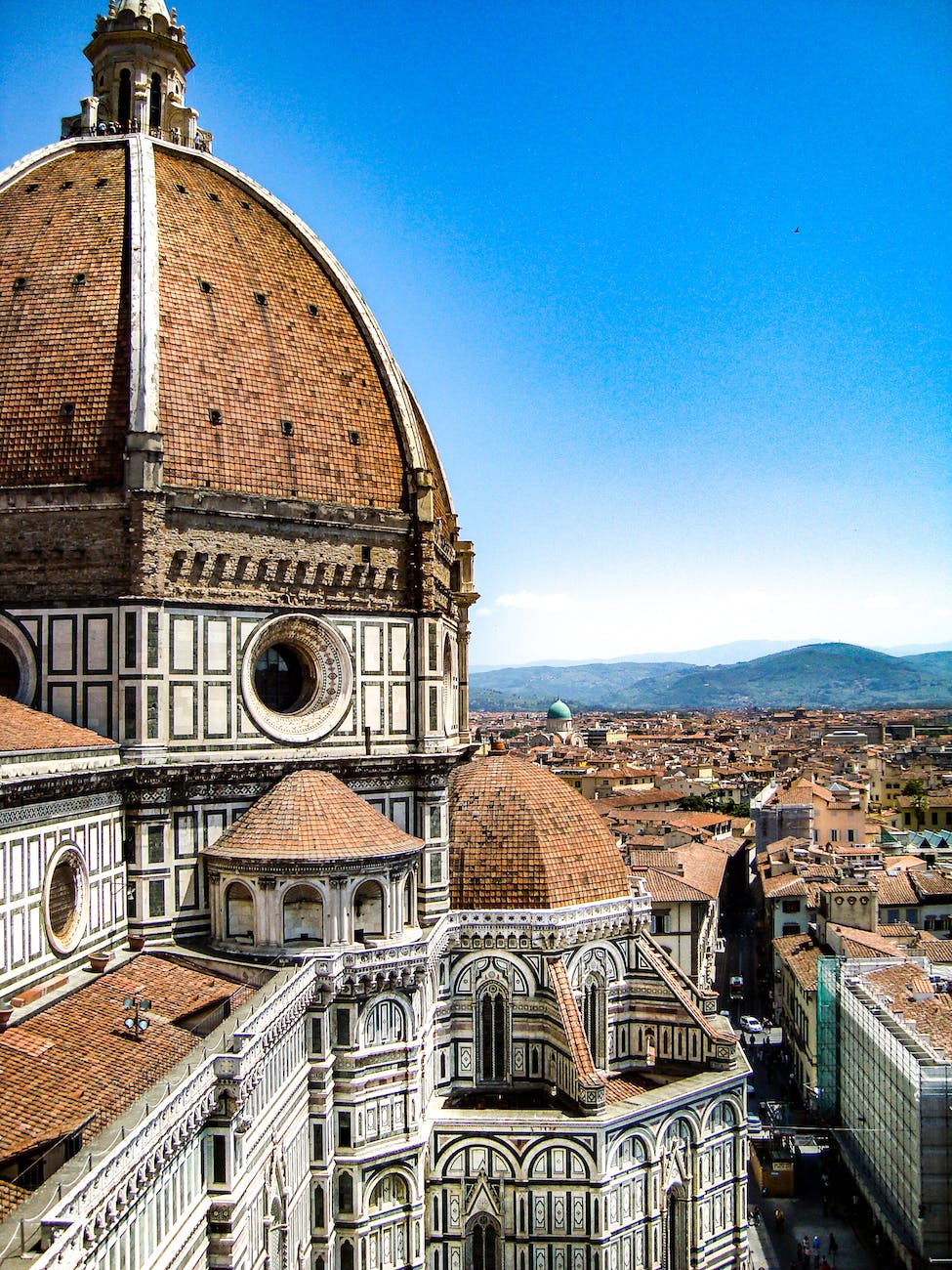 brown and white painted cathedral roof overlooking city and mountain under blue sky